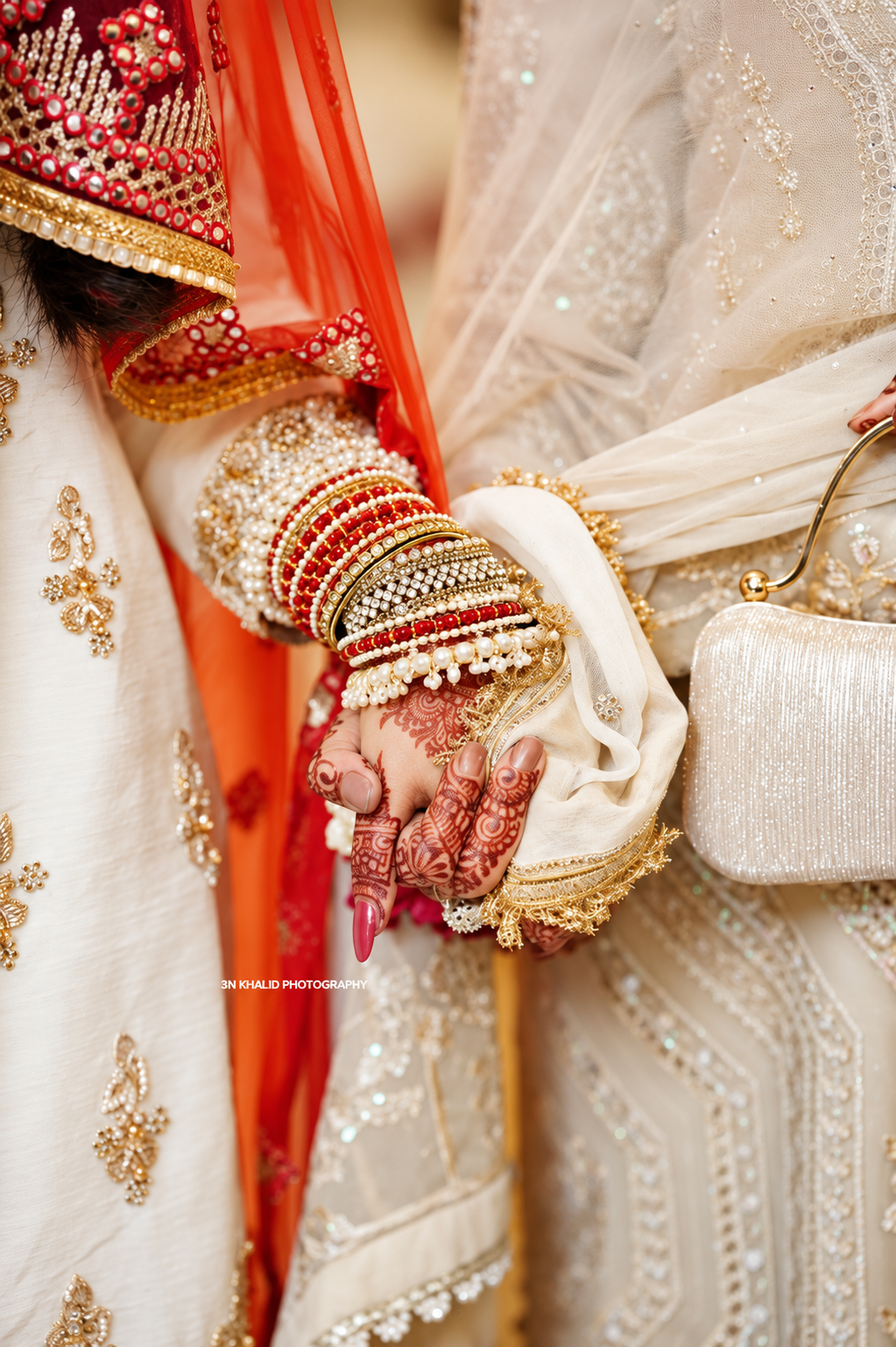 Close-up of the couple’s hands with wedding jewellery and floral details