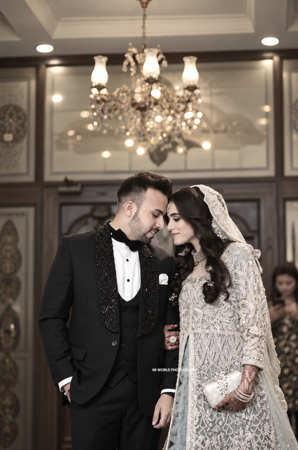 Bride and groom gently touching foreheads beneath a chandelier