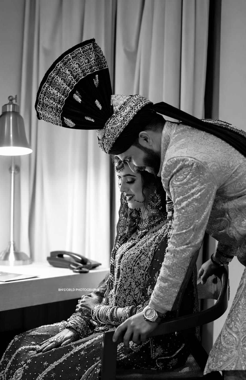 Groom leaning gently toward his seated bride in a black-and-white wedding portrait