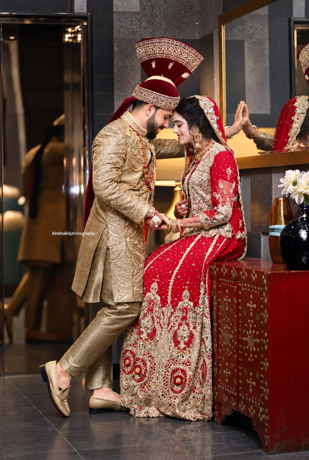 Bride in red and groom in a gold sherwani sharing a quiet wedding moment